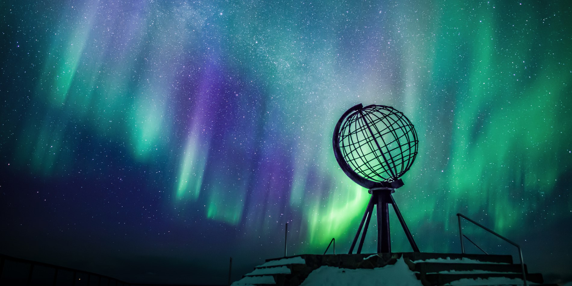North Cape monument with blue and green northern lights in the background.