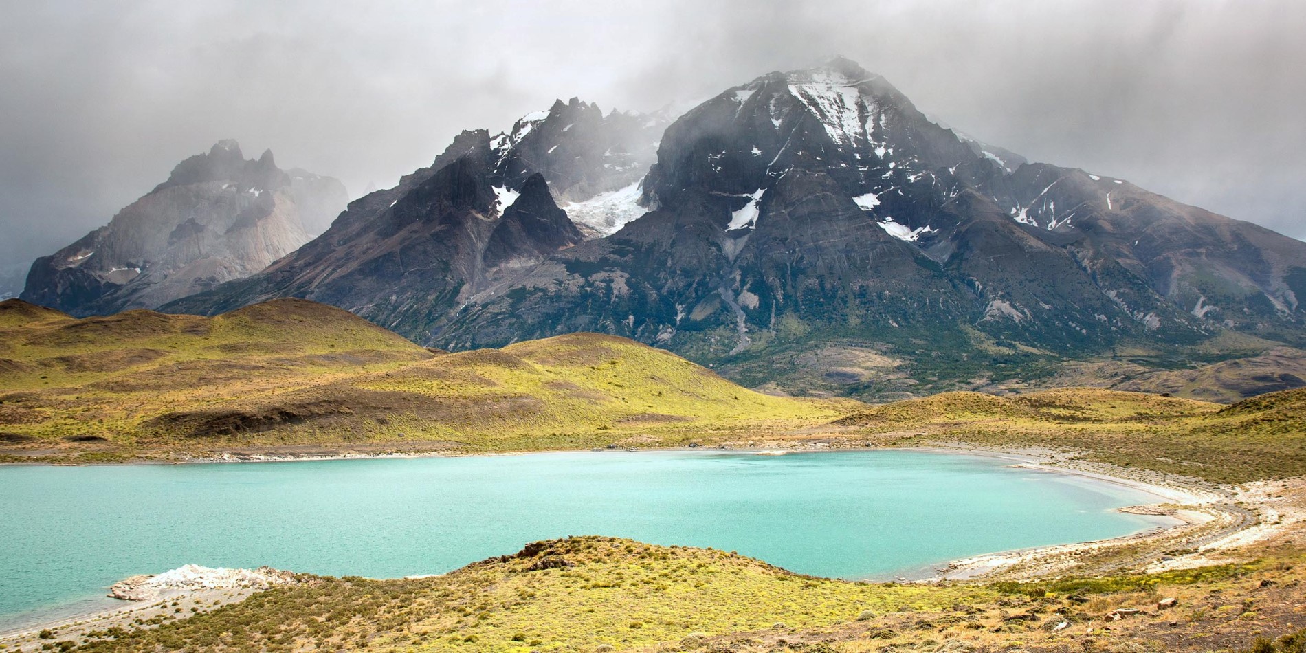 A body of water with Torres del Paine National Park in the background