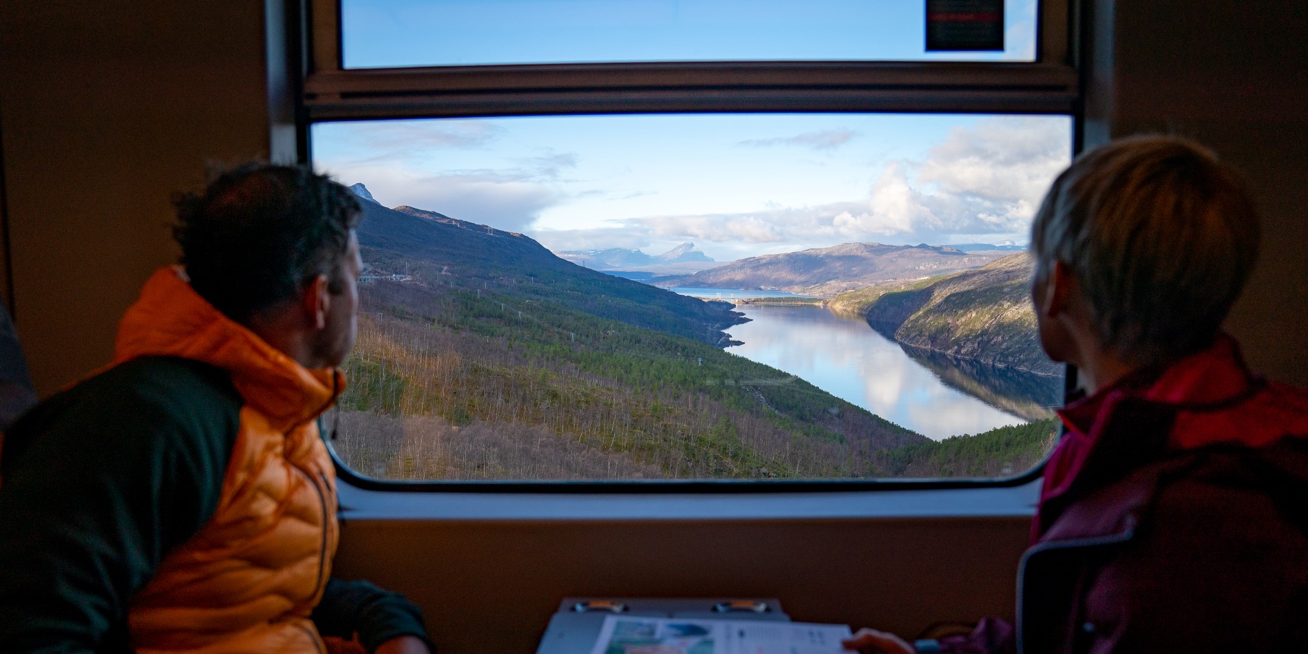 Ein Paar blickt aus dem Fenster des Arctic Trains – auf einen unterhalb gelegenen See