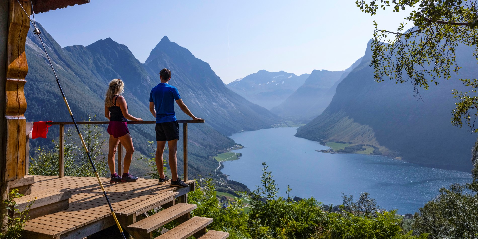 Ein Paar steht auf einem Aussichtspunkt mit Blick auf den Hjørundfjord. Westküste, Norwegen