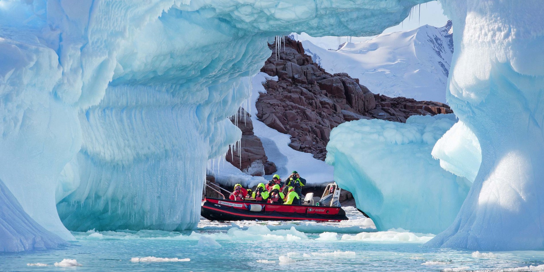 Gruppe von Touristen in kleinen Boot unter spektakulären Eisformationen